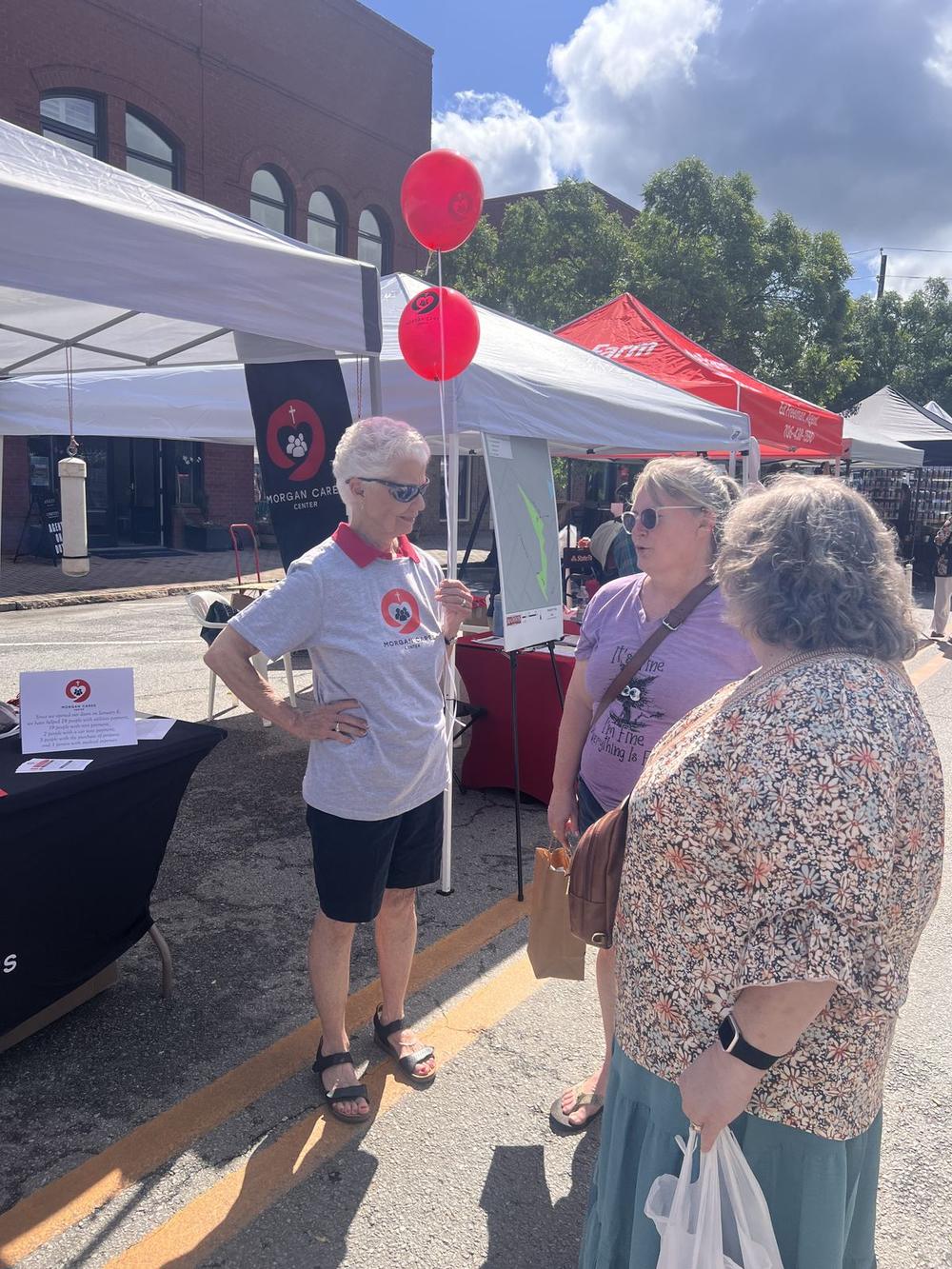 A Morgan Cares Center volunteer talking with two residents at a community event.